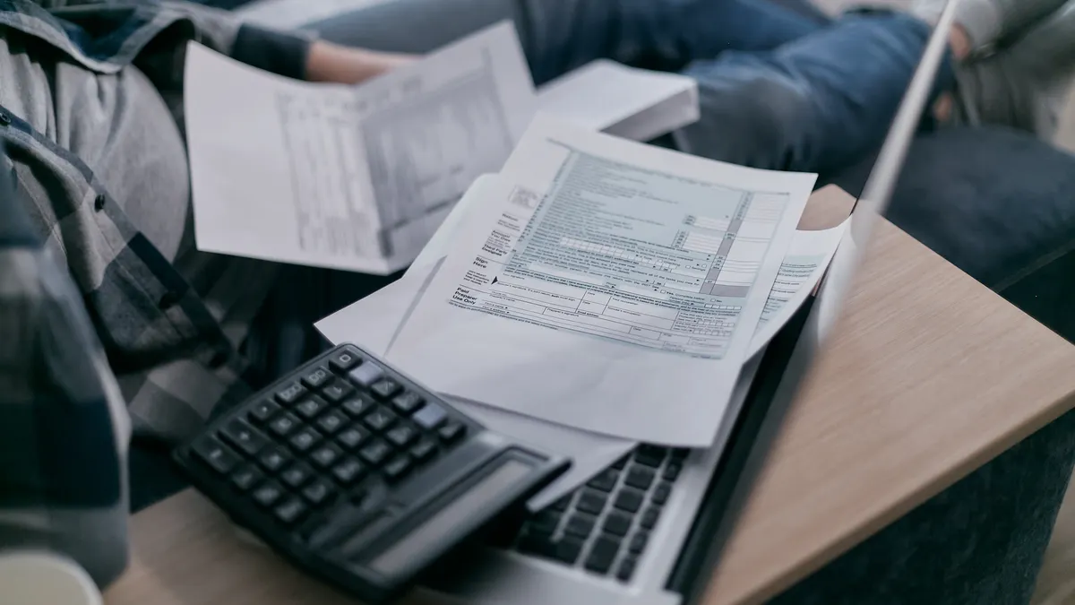 Calculator and tax paperwork on a laptop