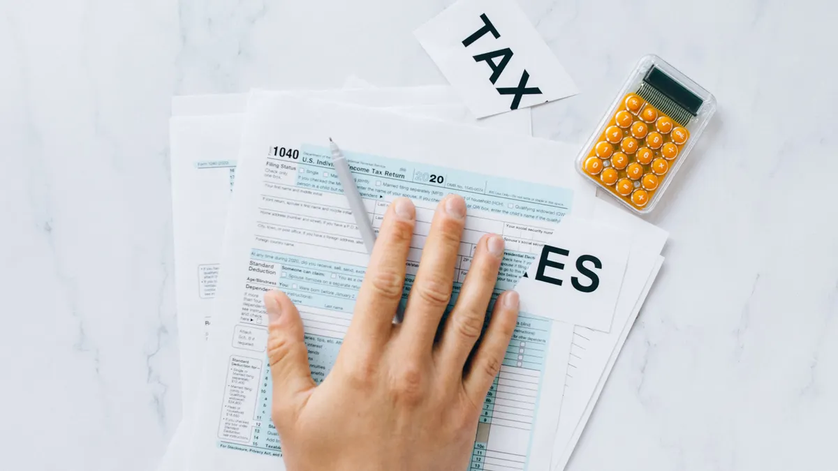 Hand reviewing tax forms with calculator