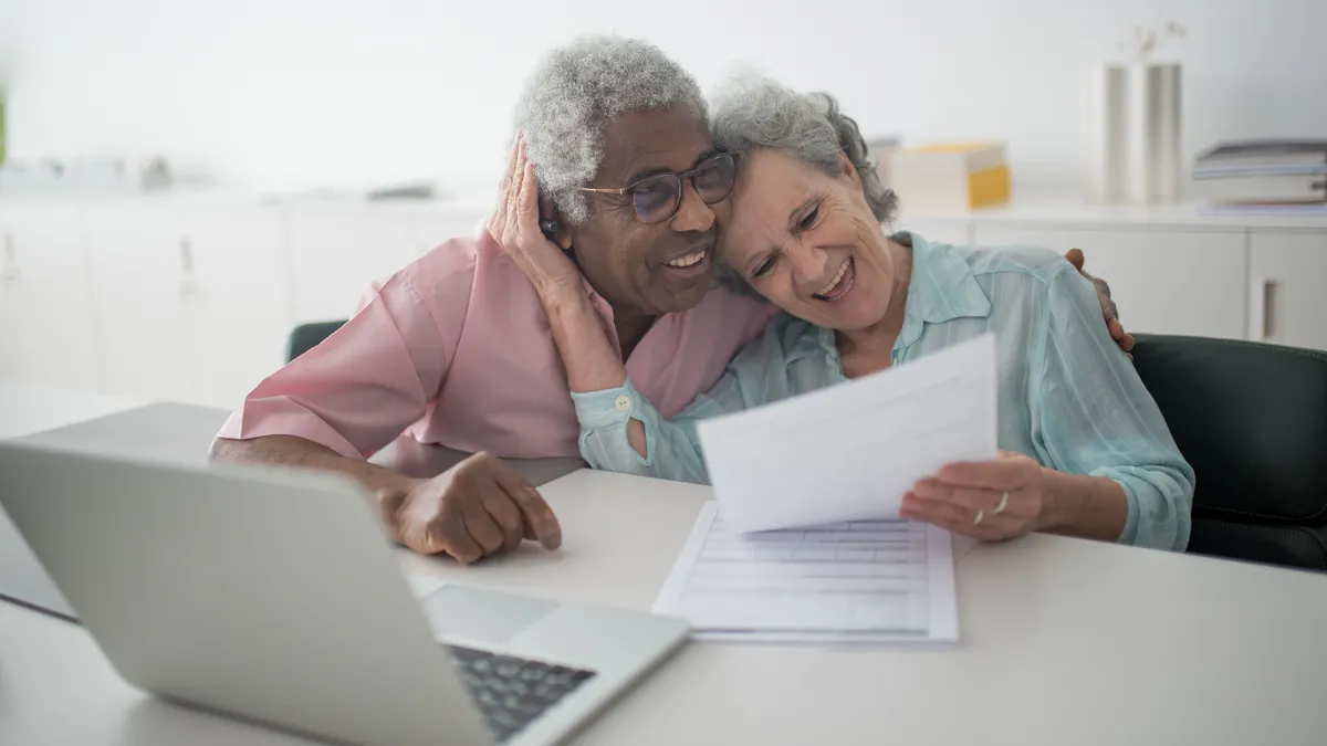 older couple reviewing documents beside a laptop