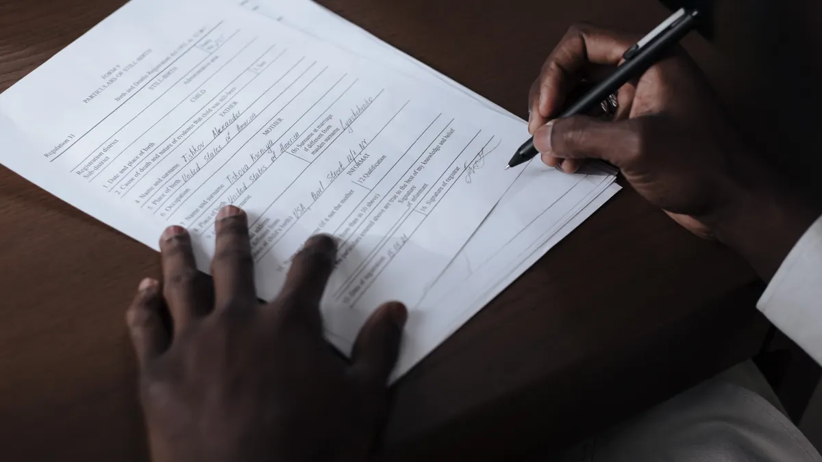 person filling out a form with a pen