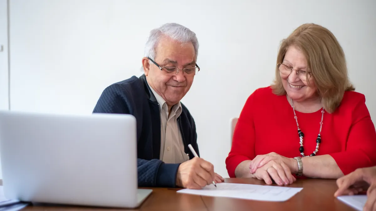 older couple signing financial paperwork with advisor